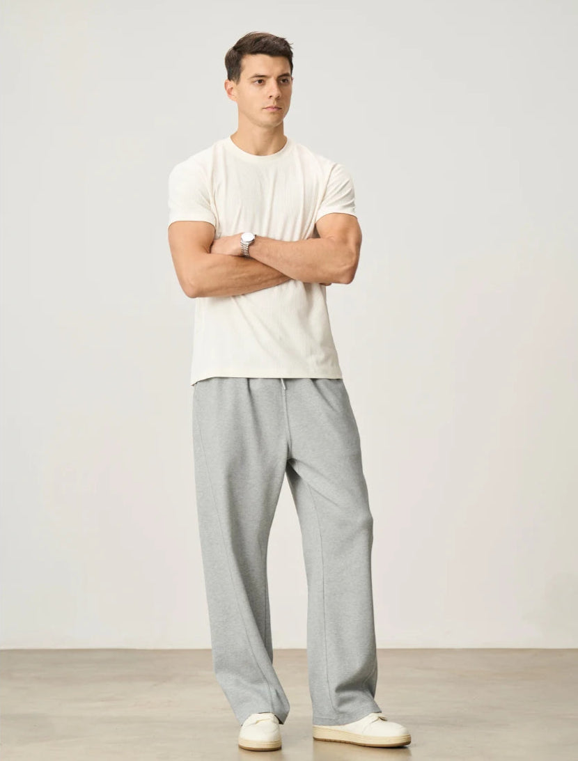 CIIVET - Model wearing a white t-shirt and grey pants standing against a plain background