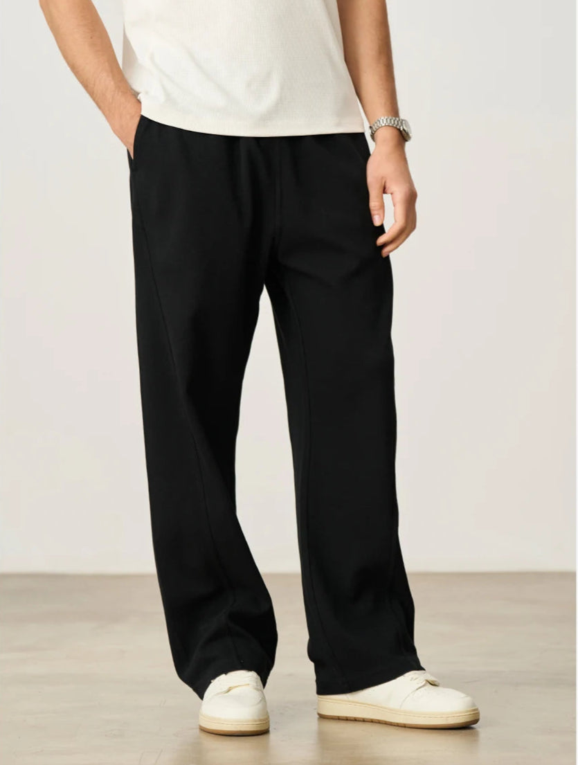 CIIVET - Model wearing black pants and a white shirt against a plain background